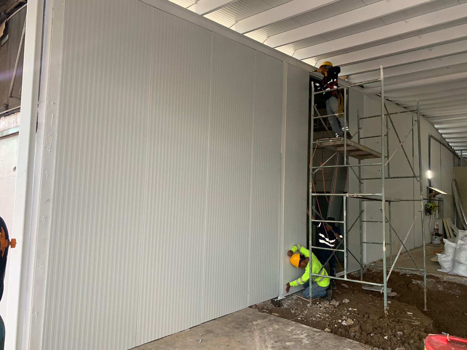 Técnicos instalando pared de panel sándwich Europanel en proyecto comercial de Panamá, con refuerzo estructural y sellado poliuretano.